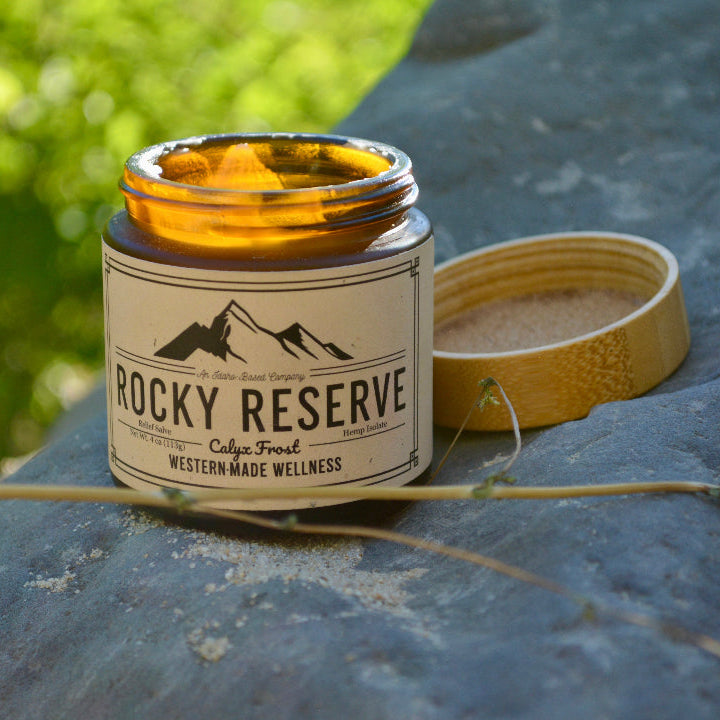 Candle labeled 'Rocky Reserve' on a stone surface with natural background