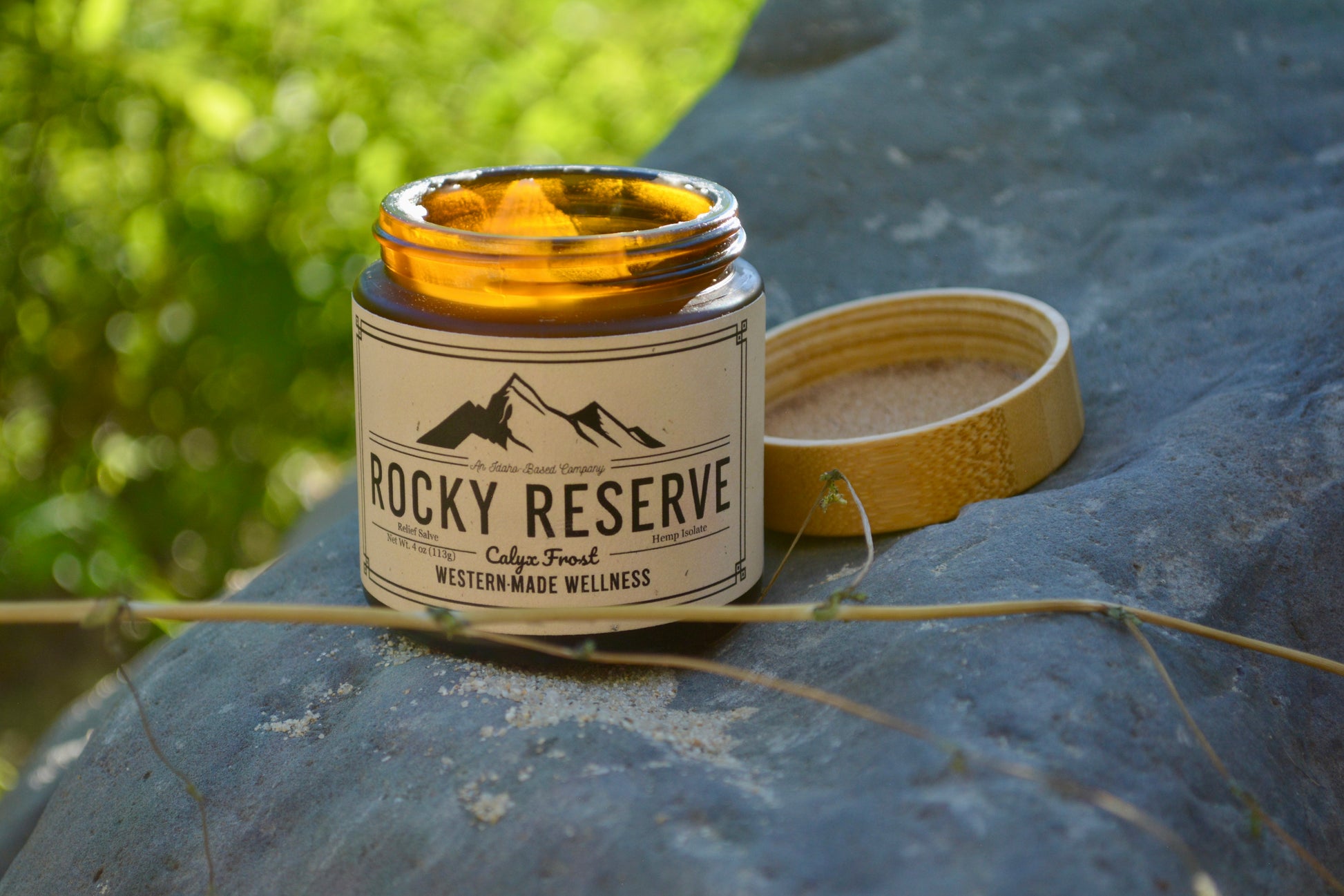 Candle labeled 'Rocky Reserve' on a stone surface with natural background